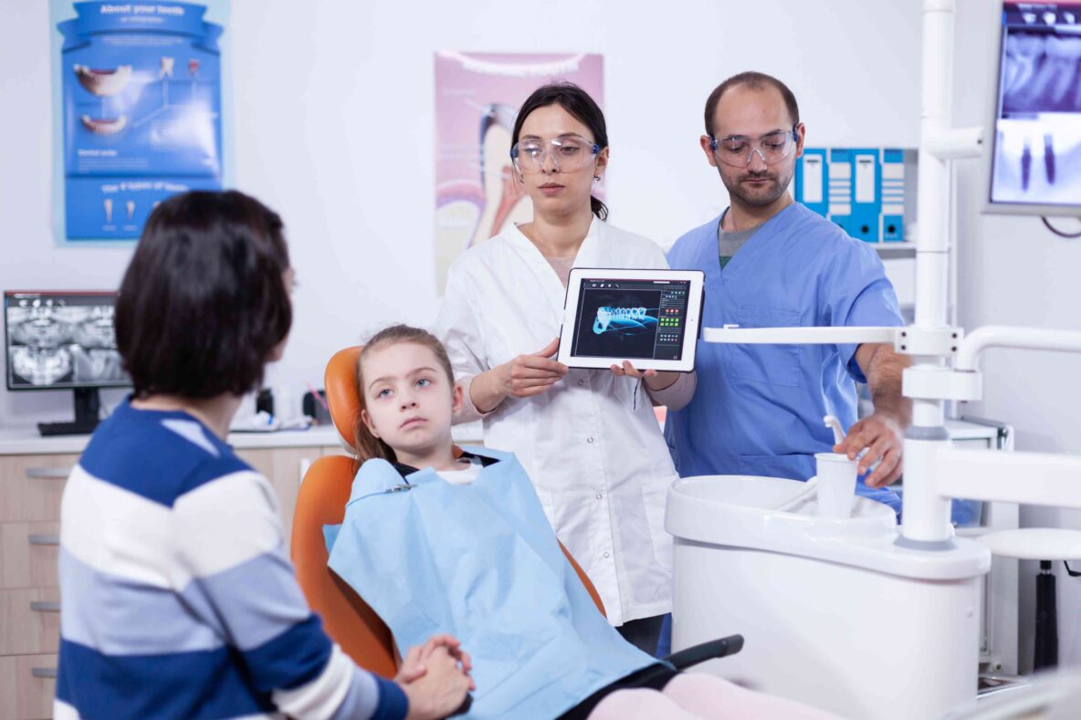Dentist explaining a child's dental X-ray to a parent.