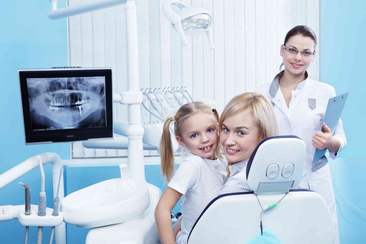 Mother and child smiling with dentist during a dental visit.